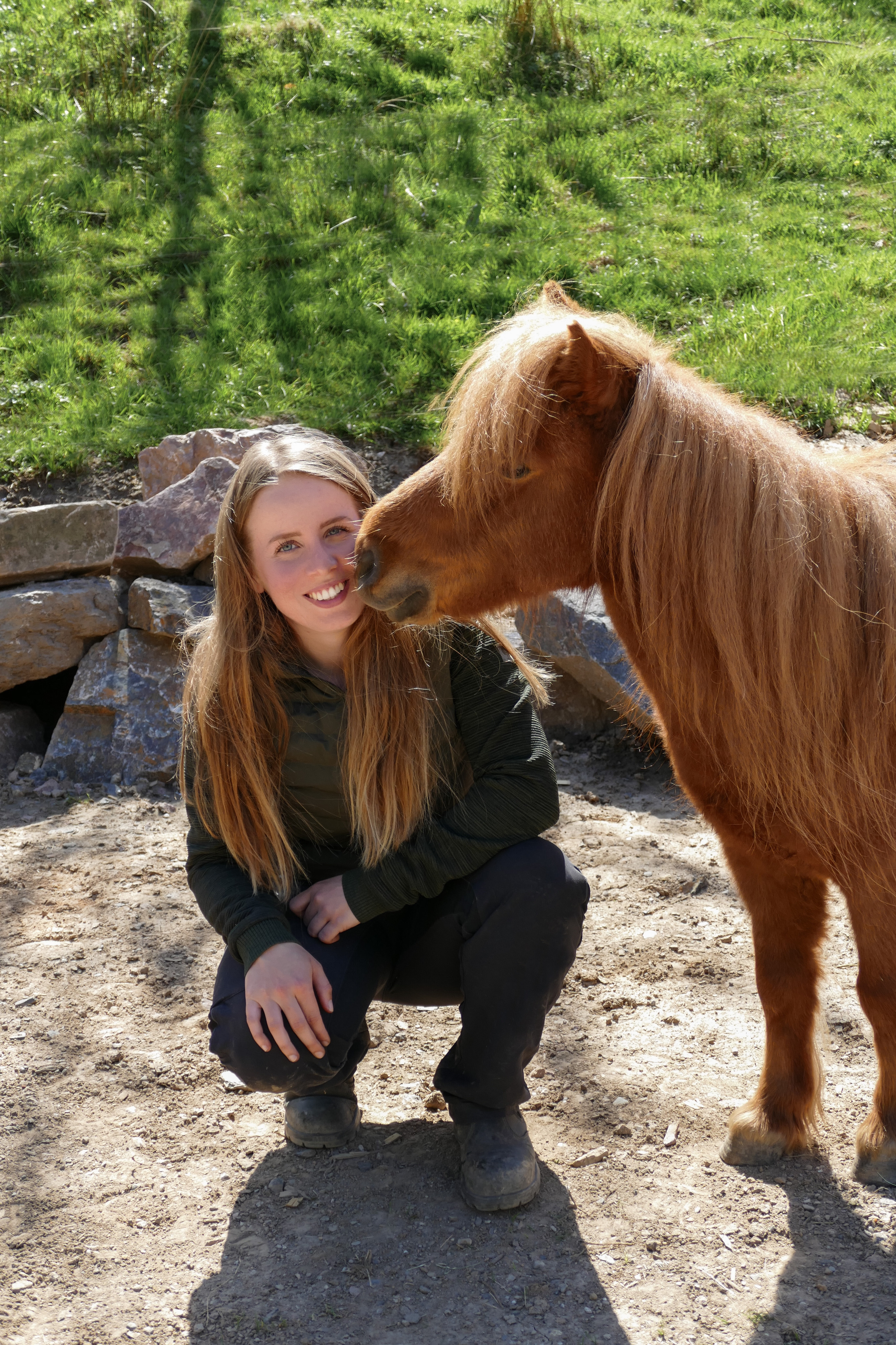 Katrin hockt lächelnd neben ihrem Mini-Shetty Herr Gimli, der sie anstupst