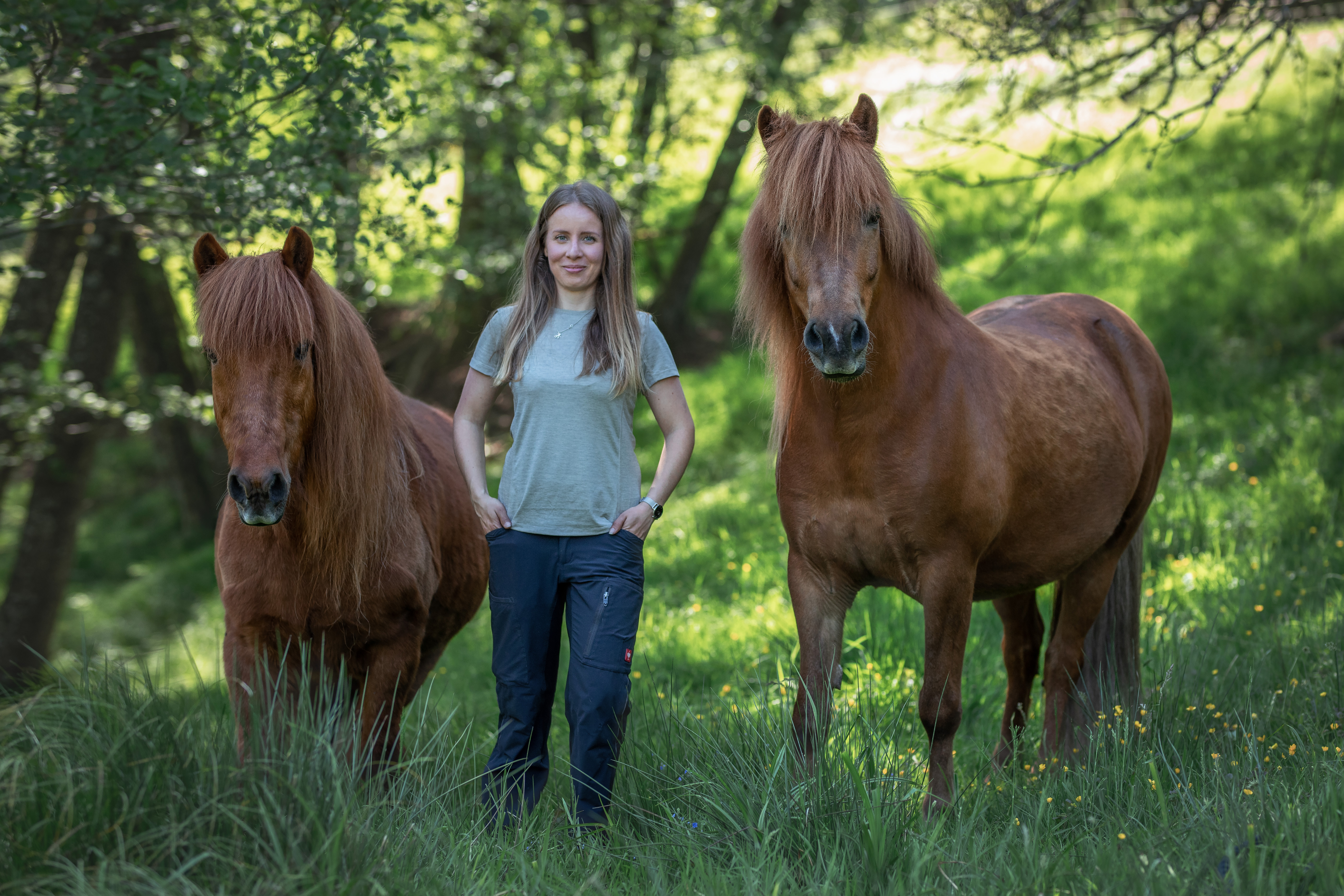 Katrin steht zwischen ihren Isländern Leynir (links) und Lennox (rechts) auf einer Wiese